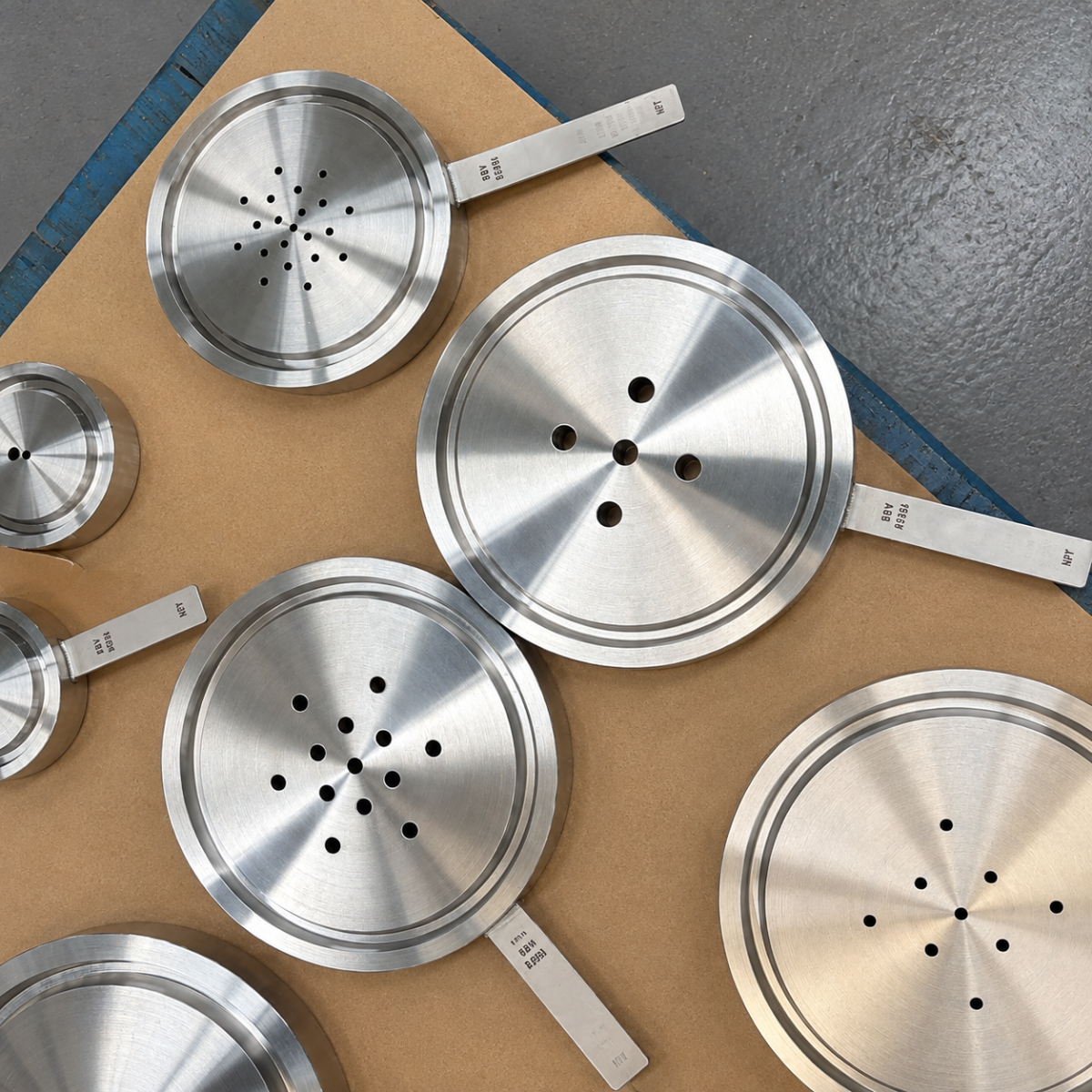Precision-machined stainless steel orifice plates arranged on a workshop table
