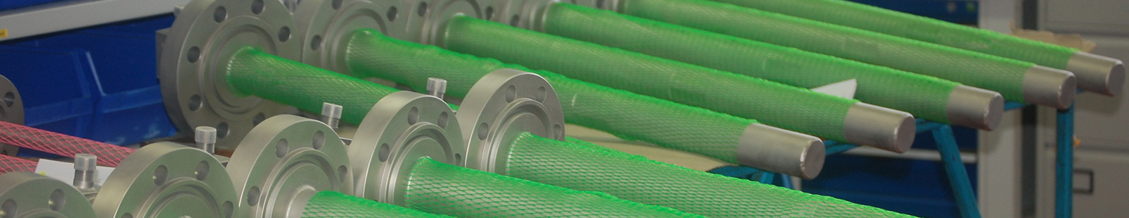 Machined industrial shafts with flanged ends and green protective mesh