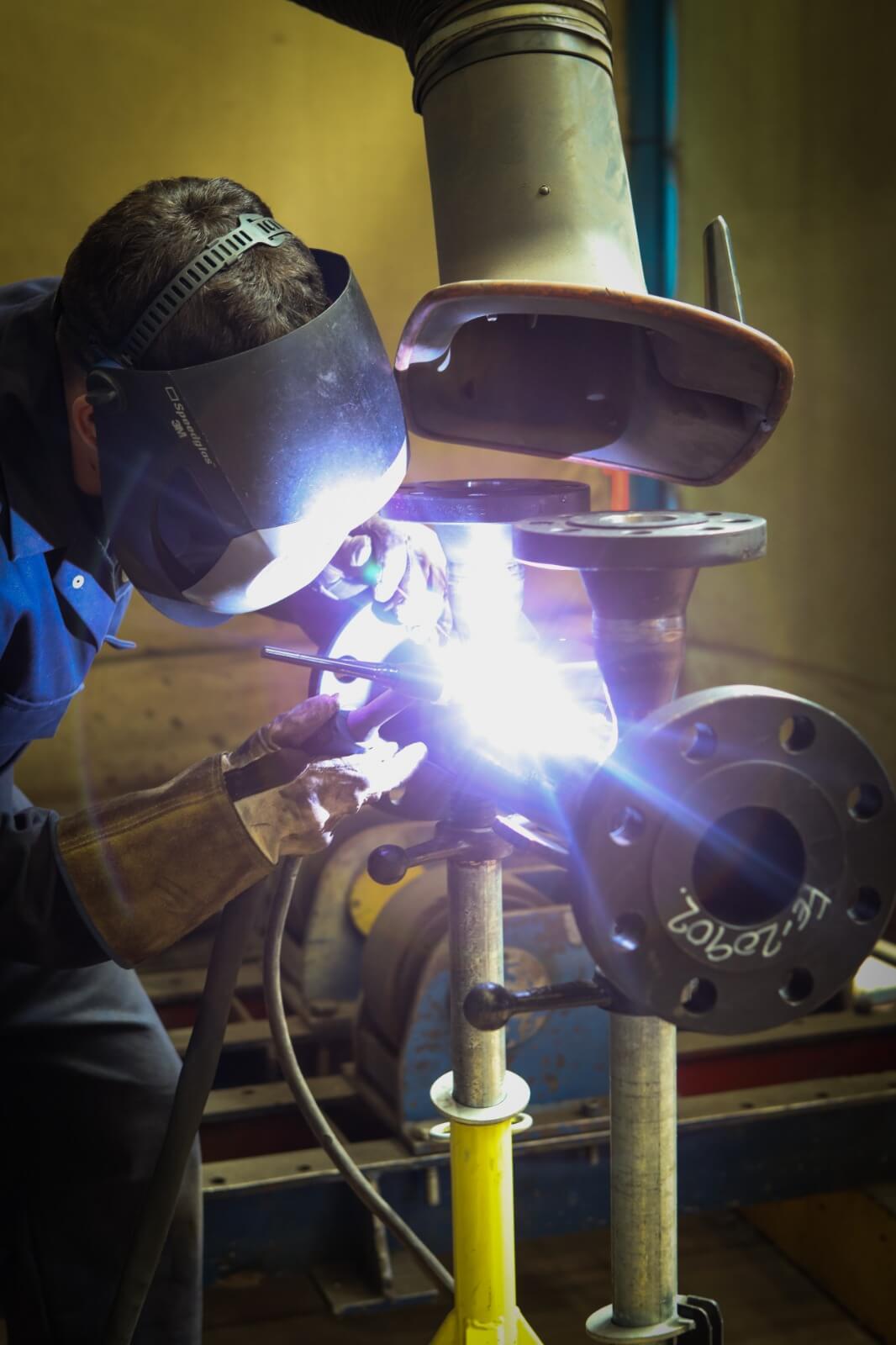 Welder working on a flanged pipe component