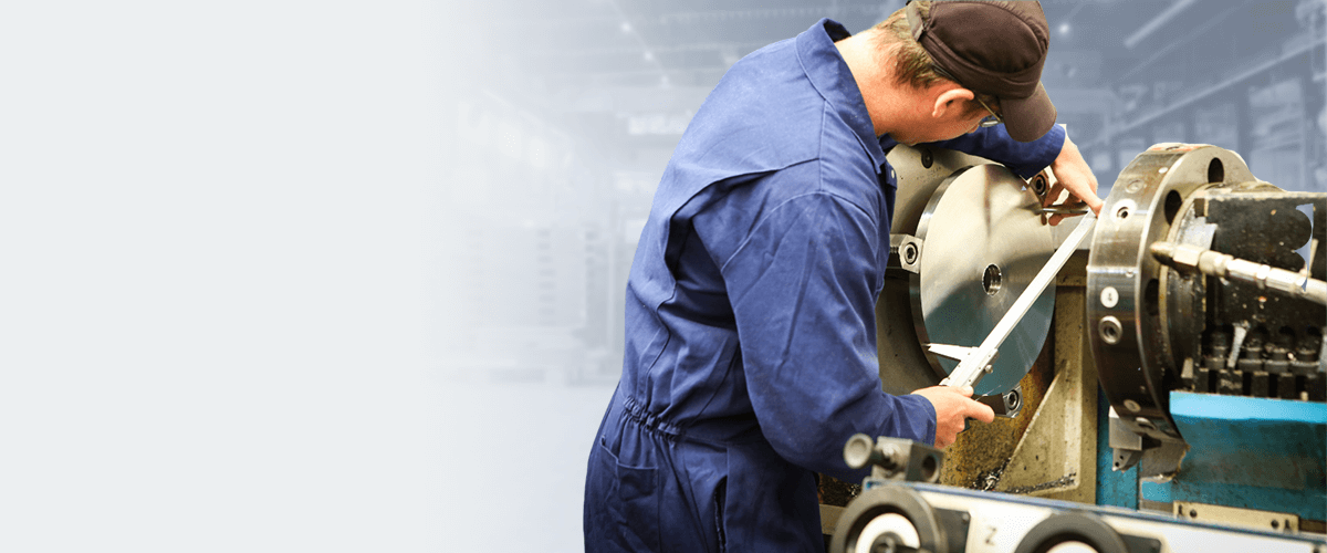 Machinist using a caliper to measure a component on a lathe